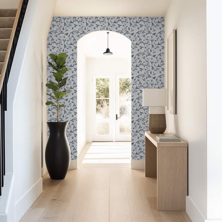 Hallway with blue dandelion and lily floral wallpaper, natural wood console, and plant.