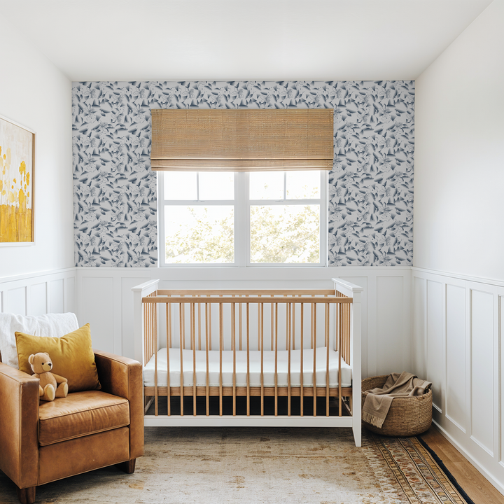 Nursery with blue dandelion and lily wallpaper, wooden crib, and leather chair.